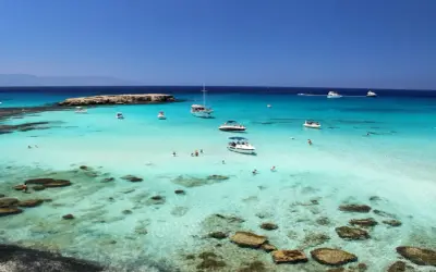 Piękne cypr plaże z turkusową wodą, łodziami i ludźmi kąpiącymi się w morzu.