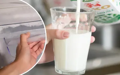 En hand öppnar en frys med frost. Bredvid hälls filmjölk upp i ett glas.
