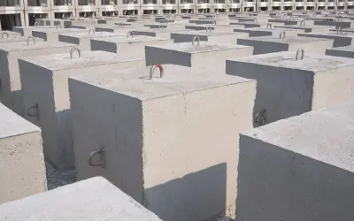 Rząd betonowych bloków, każdy kubik betonu z metalowymi uchwytami, tworzy imponującą strukturę.