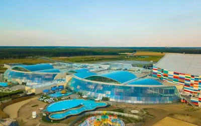Największy aquapark w Polsce z błękitnymi dachami i kolorowym budynkiem. Widać baseny, zjeżdżalnie i plac zabaw.