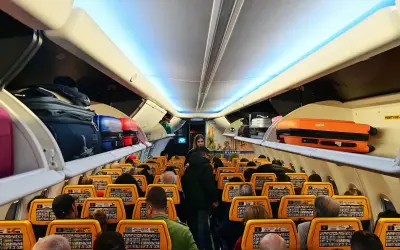Wnętrze samolotu Ryanair, bagaże na półkach. Gdzie znajdę numer lotu Ryanair? Na ekranach przed siedzeniami.