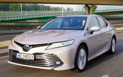 Elegancka Toyota Camry Hybrid w kolorze szampańskim na drodze. Sprawdź atrakcyjną toyota camry cena.