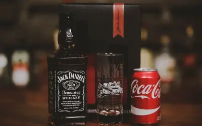 Zestaw na drinka: butelka Jack Daniel's, szklanka z logo destylarni i puszka Coca-Coli. Idealny na wieczór z klasycznym jack and coke.