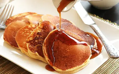 Pancakes dorati, preparati con bicarbonato al posto del lievito, vengono irrorati da uno sciroppo ambrato.