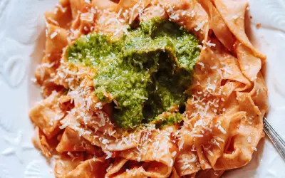 Pappardelle all'arrabbiata z zielonym pesto i parmezanem. Szerokie wstążki makaronu w sosie pomidorowym, przykryte intensywnym, zielonym pesto.