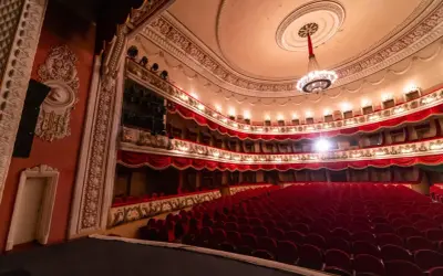 Wnętrze teatru z czerwonymi fotelami i bogato zdobionymi lożami. Czekam na pierwszą arię.