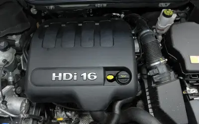 Silnik 2.0 HDi w Citroenie C5. Widoczna czarna pokrywa silnika z napisem "HDi 16" i żółte korki.