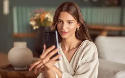 Kobieta robi selfie w lustrze, ale jej twarz jest zasłonięta przez telefon.