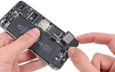 Dłonie trzymają otwarty telefon, wyjmując głośnik. Dowiedz się, jak sprawdzić głośnik w telefonie, gdy masz dostęp do jego wnętrza.