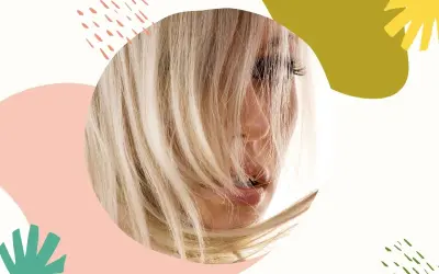 Blond włosy, które wyglądają na suche po farbowaniu, opadają na twarz kobiety. Tło ozdobione jest abstrakcyjnymi kształtami.