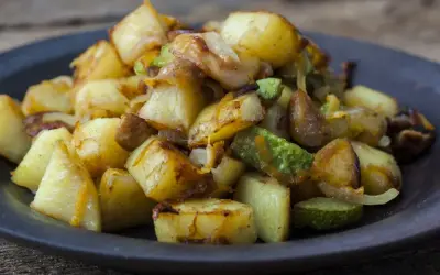 Un piatto invitante di patate e zucchine al forno, dorate e saporite, pronte per essere gustate.