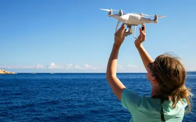 Frau hält Drohne über dem Meer in Kroatien, bereit zum Fliegen.