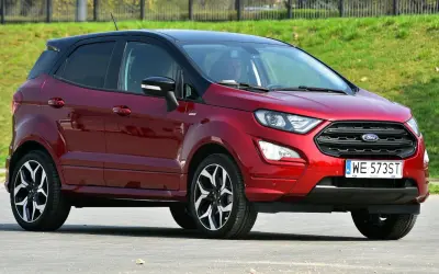 Czerwony Ford EcoSport z czarnym dachem, zaparkowany na tle zielonego zbocza.