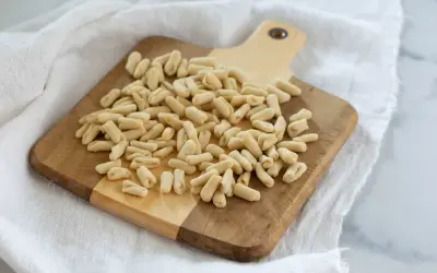 Un mucchio di cavatelli pugliesi freschi su un tagliere di legno, pronti per essere cucinati.