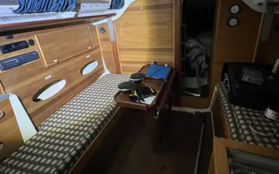 Intérieur d'un voilier Trident 80. Banquette, table pliante, rangement et couchette.