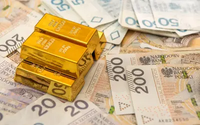 Sztabki złota na stosie polskich banknotów. Rozważasz sprzedaż złota i zastanawiasz się nad podatkiem?