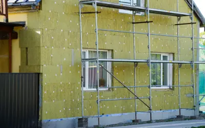 Dom w trakcie termomodernizacji, ocieplany wełną mineralną. Widać rusztowania i fragmenty starego muru pruskiego.