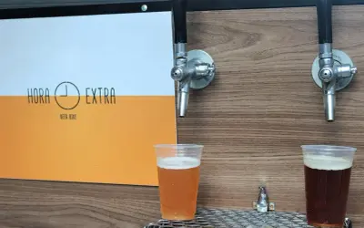 Dwa piwa w plastikowych kubkach pod kranikami. Jedno jasne, drugie ciemne. Logo "Hora Extra Beer Bike" z boku. Idealne na piwo bez chmielu.