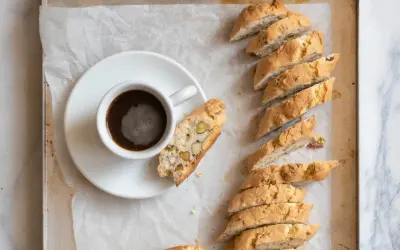 En kopp kaffe bredvid en rad med italiensk mandelskorpa, bakad med nötter och pistagenötter.