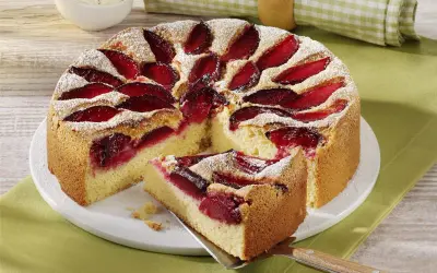 Szybkie ciasto ze śliwkami na oleju, posypane cukrem pudrem, z kawałkiem na łopatce. Idealne na deser.