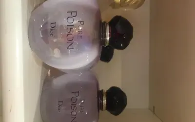 Dwa flakony perfum Pure Poison Dior 100ml, każdy z fioletową poświatą i czarnym korkiem.
