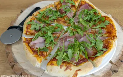 Pyszna pizza z rukolą i szynką, gotowa do podania. Idealne składniki na pizzę dla każdego smakosza.