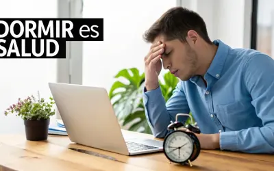 Joven con dolor de cabeza frente a su laptop, buscando trucos para dormir mejor. El reloj marca la hora.