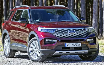 Czerwony Ford Explorer, jeden z wielu modeli tej marki, zaparkowany na leśnej drodze.