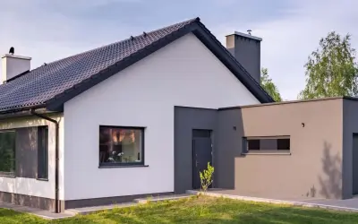 Nowoczesny dom z białymi i grafitowymi ścianami, prezentujący najmodniejsze kolory elewacji. Dachówka w ciemnym kolorze.