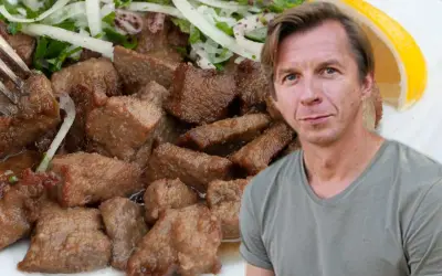 Mężczyzna obok talerza z wątróbką w sosie z cebulą i cytryną. Wątróbka w mleku jest miękka i delikatna.