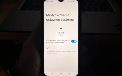 Ekran telefonu pokazuje ustawienia systemu, gdzie można sprawdzić, jak włączyć kamerę w telefonie.