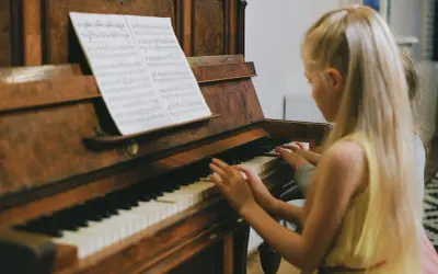 Dzieci grają na keyboardzie, patrząc na nuty literowe.