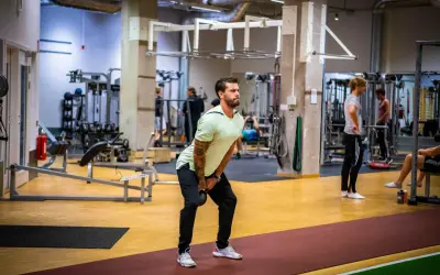 Man utför ett helkroppspass på gym med kettlebell.