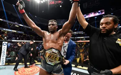 En segerrik UFC-mästare, med bälte och armarna i luften, firar som en riktig sumo brottare.