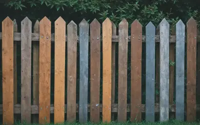 Różnobarwne, drewniane deski tworzą urokliwe, lekko zniszczone ogrodzenie. Jakie ogrodzenie, takie życie!