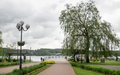 Spacer nad jeziorem w Mrągowie, z wierzbą płaczącą i kwitnącymi rabatami. Idealne miejsce na relaks i podziwianie mrągowskich atrakcji.
