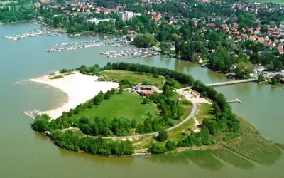 Grüne Insel mit Sandstrand und Gebäuden im Steinhuder Meer, umgeben von einem Yachthafen und einer Ortschaft.
