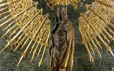 Virgen con Niño, rodeada de un resplandor dorado y joyas, evocando la solemnidad de cuando es la Pilarica.