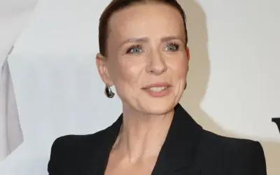 Aneta Zając w czarnej marynarce, z dużymi kolczykami, uśmiecha się. Jej partner, jeśli jest obecny, nie jest widoczny.