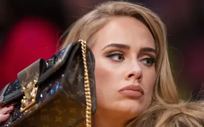 Adele z torebką na koncercie, zamyślona, z makijażem i blond włosami.