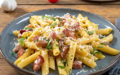 Penne rigate z chrupiącym boczkiem, posypane parmezanem i natką pietruszki. Idealny makaron z boczkiem na szybki obiad.