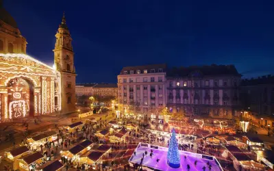Magiczny budapeszt jarmark bożonarodzeniowy. Tłumy ludzi na lodowisku i przy straganach, oświetlona bazylika w tle.