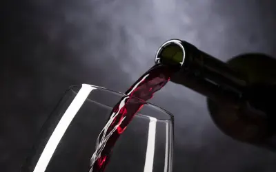 Ciemnoczerwone wino, być może najdroższe wino, leje się z butelki do kieliszka.