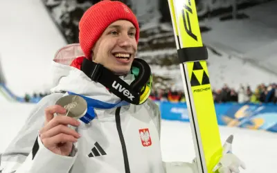 Uśmiechnięty skoczek narciarski w czerwonej czapce trzyma srebrny medal. Czy za dwa medale olimpijskie są dwie emerytury?