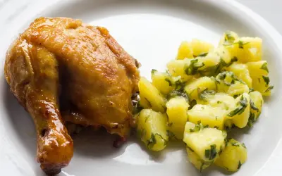Apetyczna, pieczona noga z kurczaka z ziemniakami i natką pietruszki.