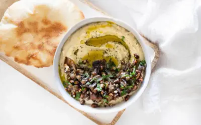 Un bol de caviar d'aubergine libanais, garni d'huile d'olive et de persil, servi avec du pain pita. Une recette savoureuse à découvrir.