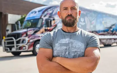 Dawid Andres, w sile wieku, z brodą, stoi przed ozdobioną ciężarówką.