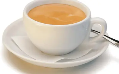 Ein kleiner brauner Kaffee mit Milchschaum in einer weißen Tasse auf einer Untertasse.