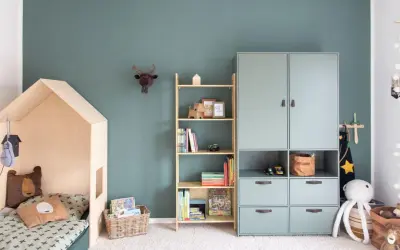 Gemütliches Kinderzimmer für Grundschulkinder mit Hausbett, Bücherregal und Spielzeug.