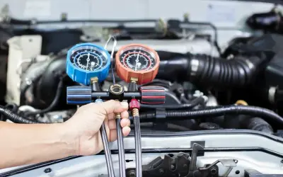 Mechanik sprawdza ciśnienie w układzie klimatyzacji, przygotowując nowy czynnik klimatyzacji do napełnienia.